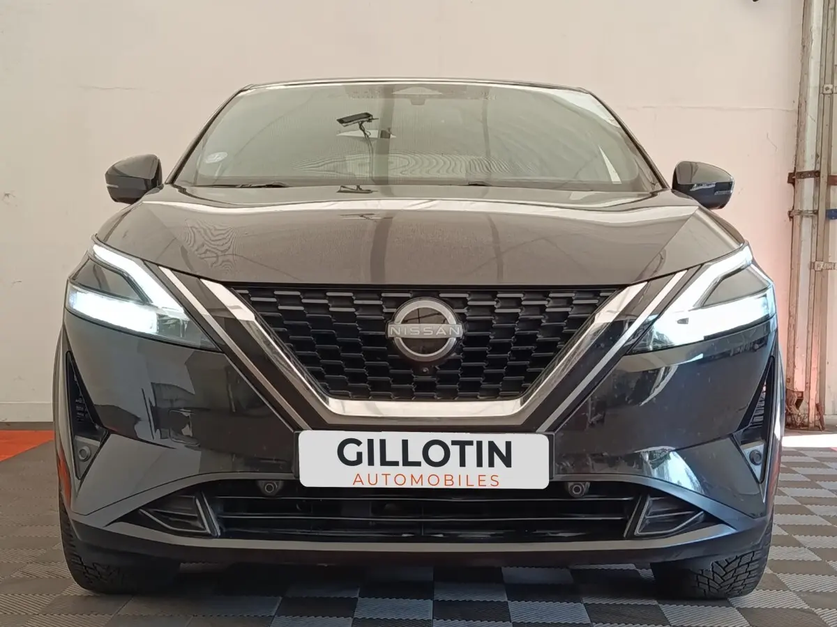 Vue avant du Nissan Qashqai noir 2023 avec phares LED allumés et calandre chromée distinctive.