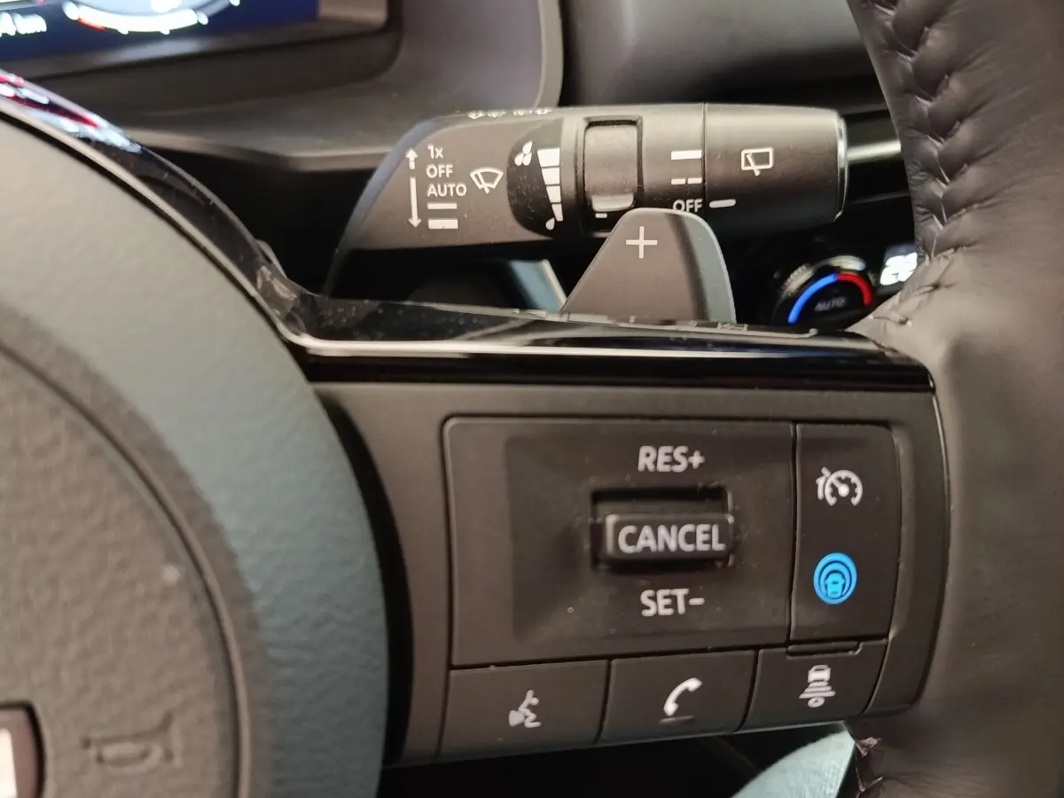 Gros plan sur les commandes au volant côté droit du Nissan Qashqai noir 2023, avec régulateur de vitesse et palettes de changement.