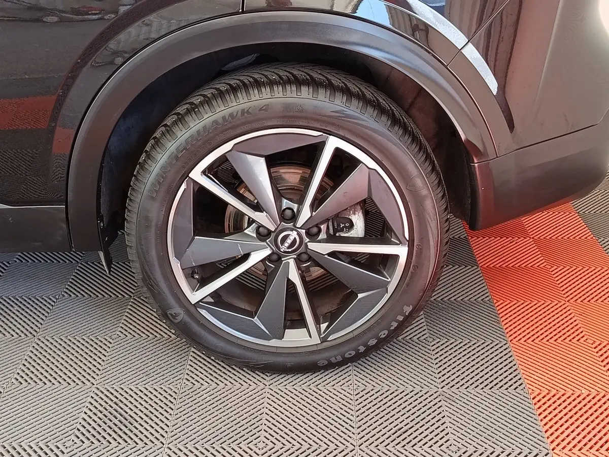 Gros plan sur la roue arrière droite noire du Nissan Qashqai 1.3 MHEV 158ch Xtronic Tekna avec jante alliage moderne.