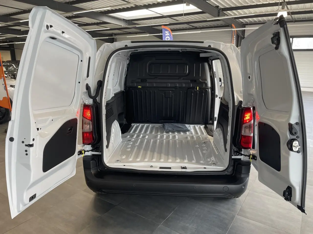 Vue arrière du Peugeot Partner blanc 2026 avec portes battantes ouvertes montrant l'espace de chargement vide et tôlé.