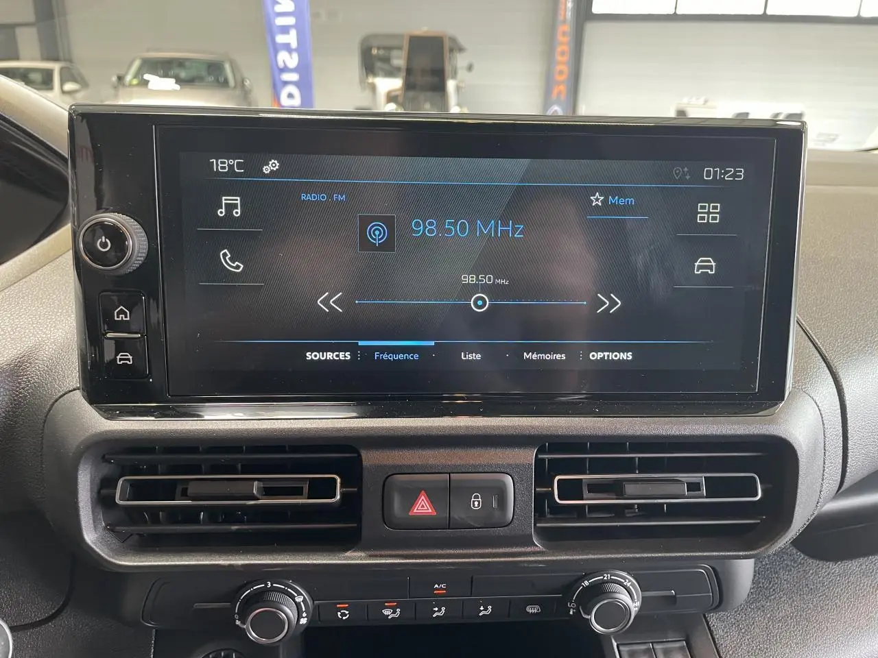 Vue intérieure du tableau de bord du Peugeot Partner blanc, avec écran tactile central affichant la radio FM à 98,50 MHz.