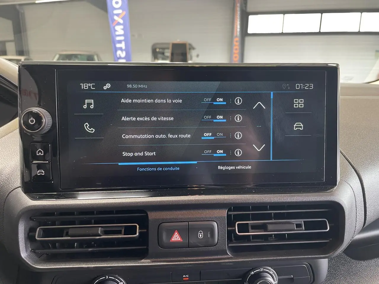 Écran tactile central du tableau de bord du Peugeot Partner blanc, affichant les aides à la conduite activées.