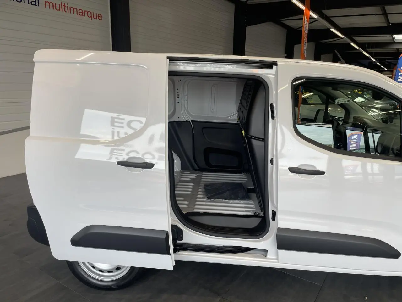 Vue latérale droite du Peugeot Partner blanc avec porte coulissante ouverte montrant l'espace de chargement vide.