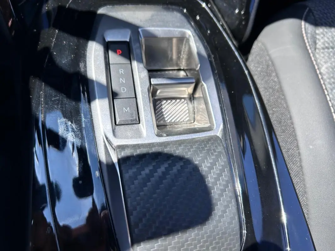 Gros plan sur la console centrale noire brillante du Peugeot 2008 Hybrid 136 e-DCS6 Allure avec sélecteur de boîte auto.