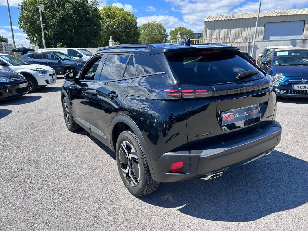 Peugeot 2008 Hybrid noir vue 3/4 arrière droit, avec barres de toit et jantes alliage 17 pouces visibles.