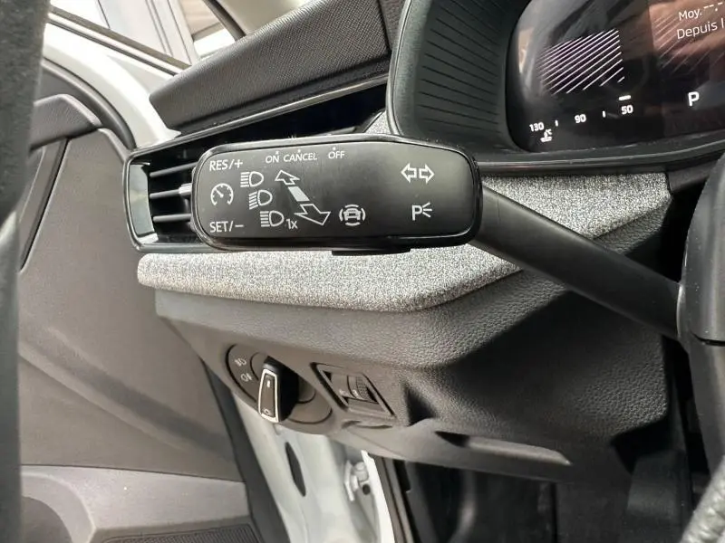 Gros plan sur la commande de régulateur de vitesse et clignotants côté gauche du tableau de bord gris d'une Skoda Scala blanc cristal.