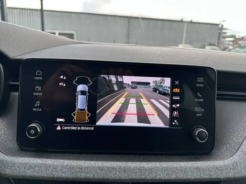 Écran tactile central de la Skoda Scala blanc, affichant la caméra de recul avec repères de stationnement colorés.