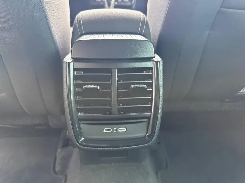 Vue rapprochée des aérateurs arrière noirs et des ports USB-C sous l'accoudoir central arrière d'un Skoda Scala blanc cristal.