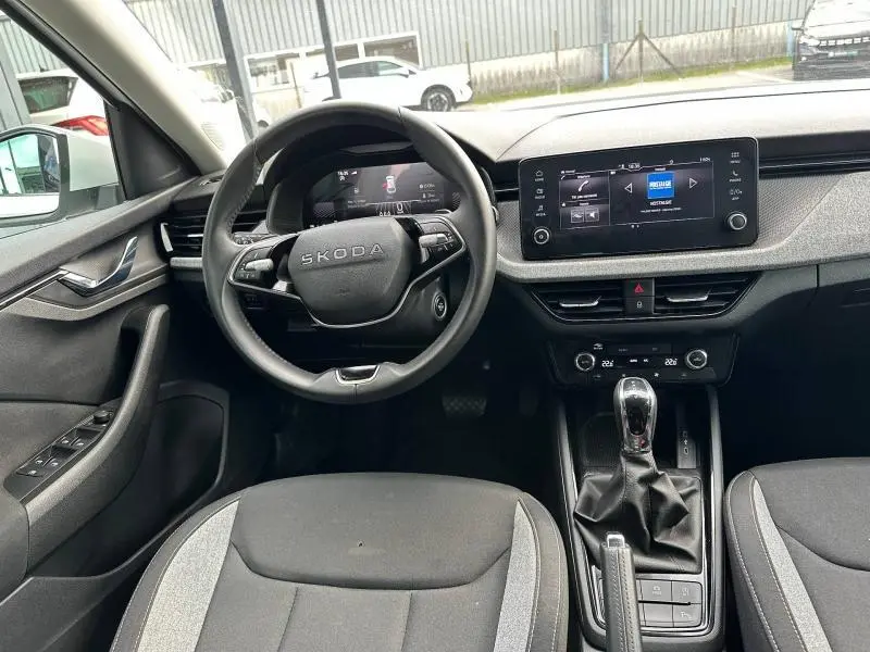 Vue intérieure avant de la Skoda Scala 2025, volant cuir multifonction, écran tactile et sellerie tissu gris/noir.