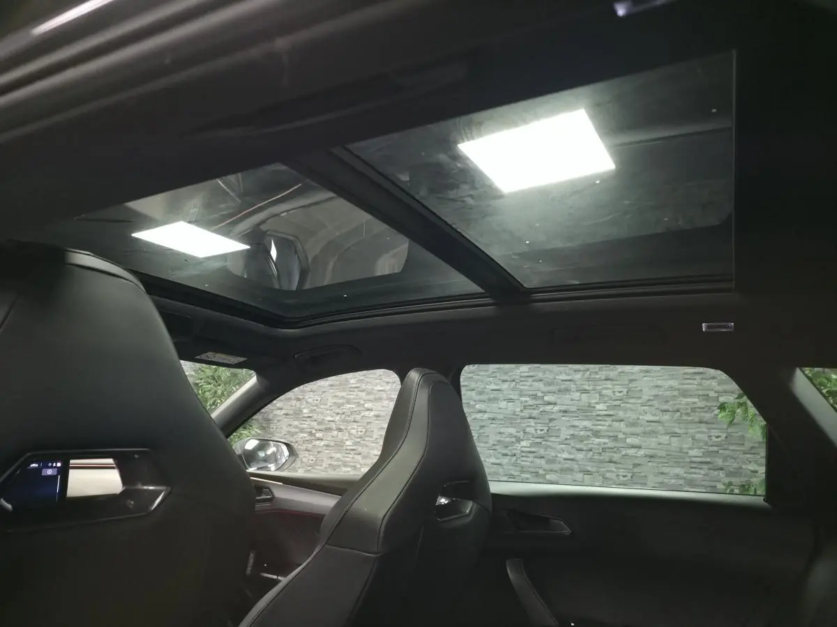 Vue intérieure du toit ouvrant panoramique et des sièges baquets noirs du Cupra Leon Sportstourer gris 2023.