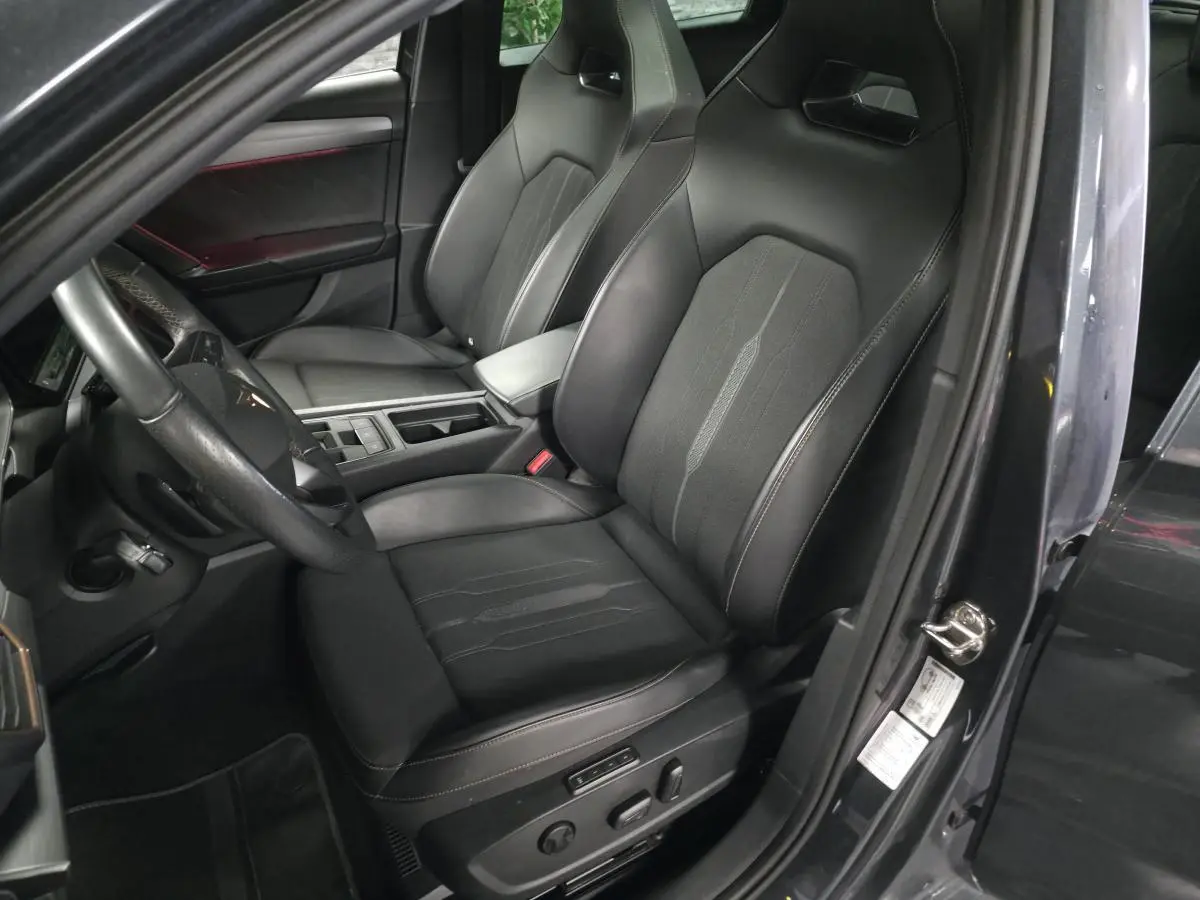 Vue intérieure côté conducteur du CUPRA Leon Sportstourer gris, mettant en valeur le siège baquet noir avec surpiqûres copper.
