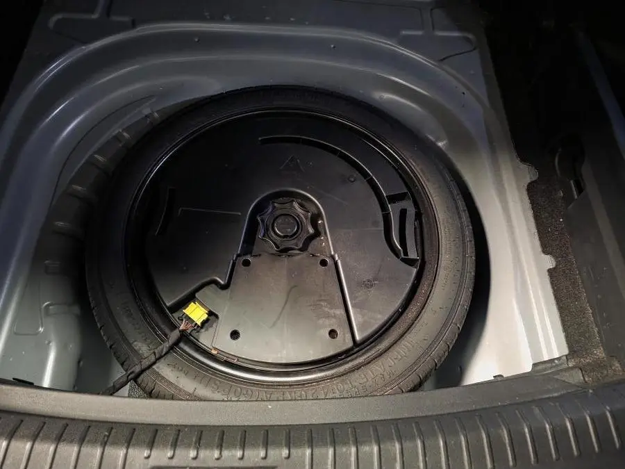 Vue plongeante sur la roue de secours dans le coffre du CUPRA Leon Sportstourer gris 2023, détail du rangement intérieur.