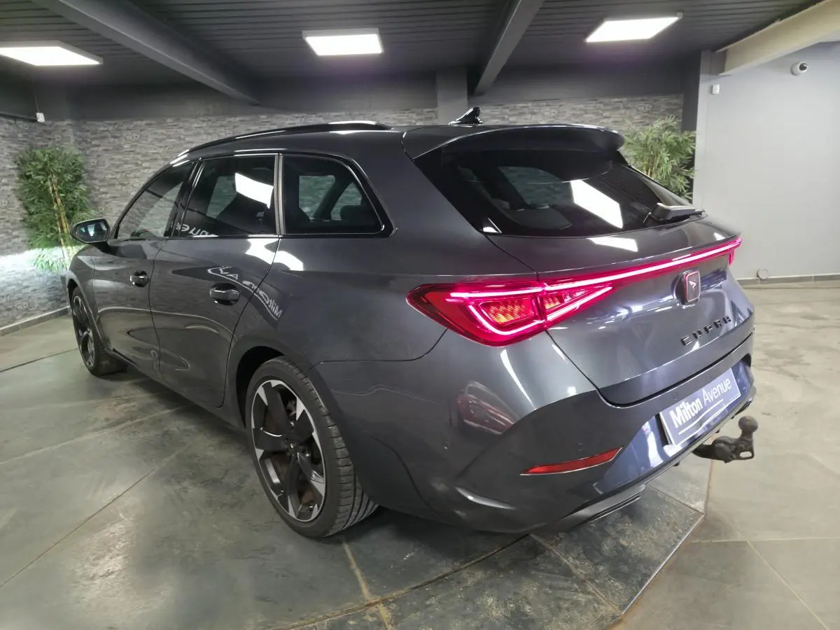 Vue 3/4 arrière droite d'une CUPRA Leon Sportstourer gris magnétique avec feux LED et crochet d'attelage escamotable.