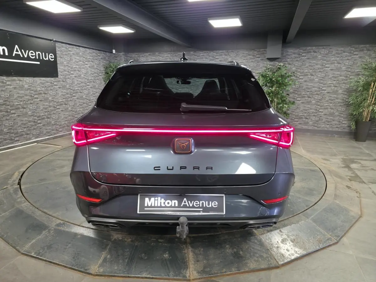 Vue arrière d'un CUPRA Leon Sportstourer gris avec feux LED en bandeau et crochet d'attelage escamotable visible.