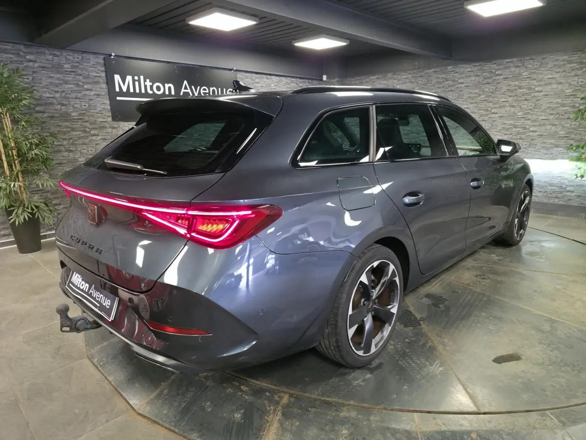 Vue 3/4 arrière droite d’une CUPRA Leon Sportstourer gris magnétique avec feux arrière LED et crochet d’attelage escamotable.