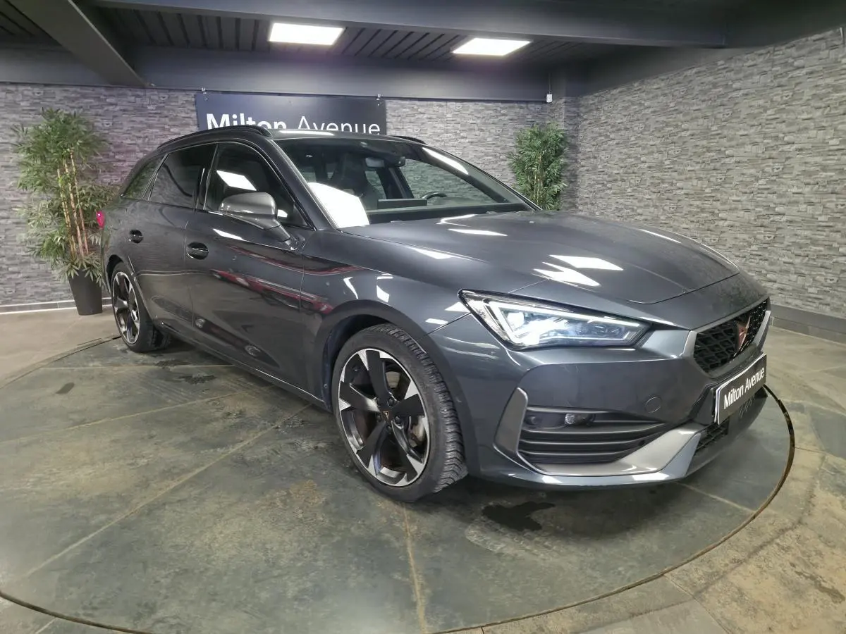 Vue 3/4 avant droite d'une CUPRA Leon Sportstourer gris métallisé avec jantes alliage noires et détails sportifs.