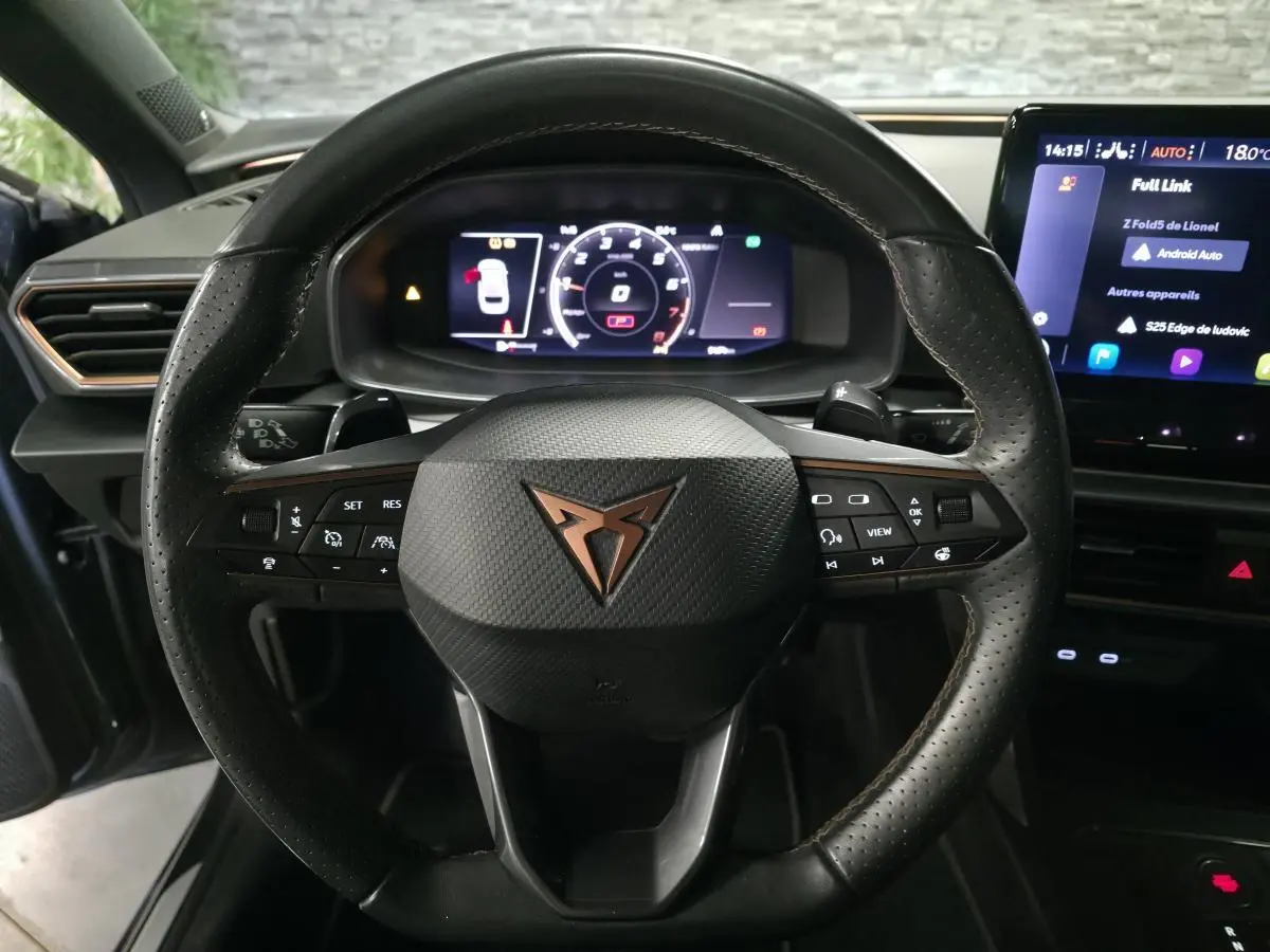 Vue rapprochée du volant cuir noir perforé avec logo CUPRA cuivre et combiné d'instruments digital couleur.