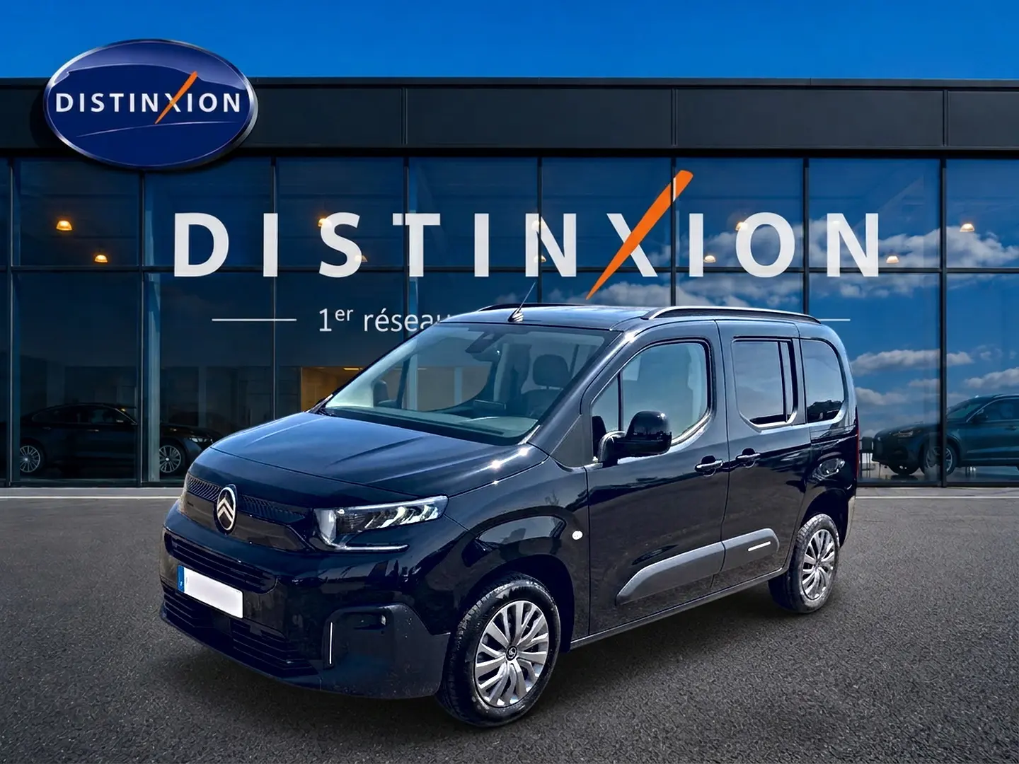 Citroën Berlingo noir vue 3/4 avant droit devant showroom Distinxion avec jantes alu et vitres teintées.