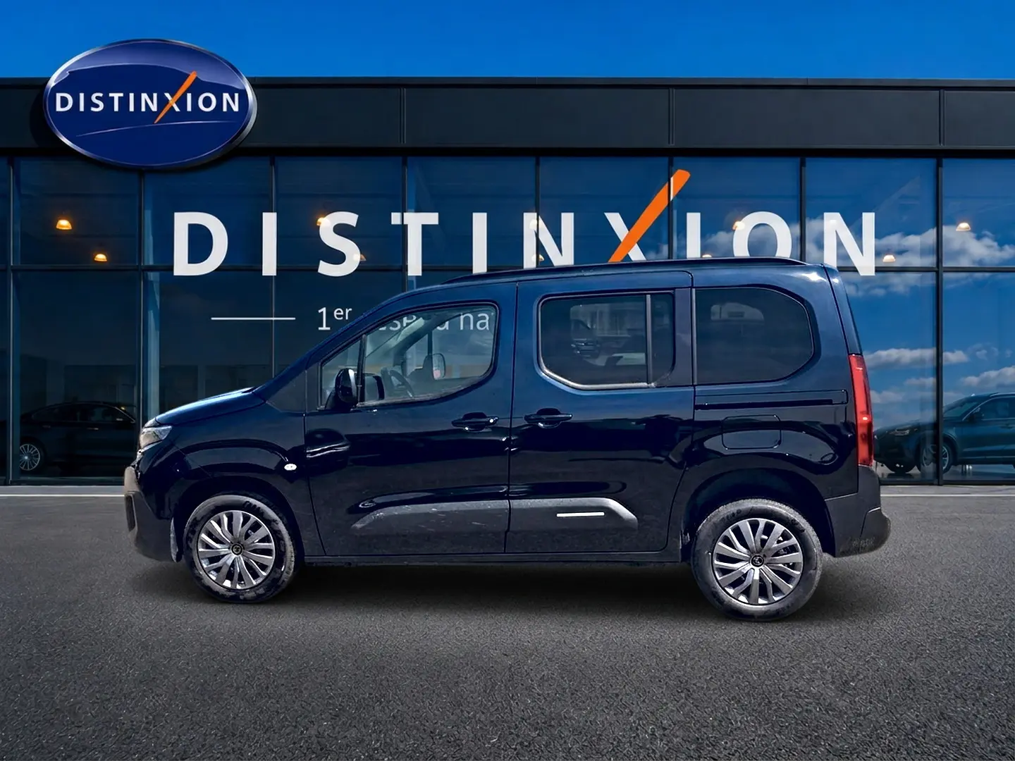 Profil droit du Citroën Berlingo noir 2026 avec barres de toit et jantes alu devant une vitrine Distinxion.