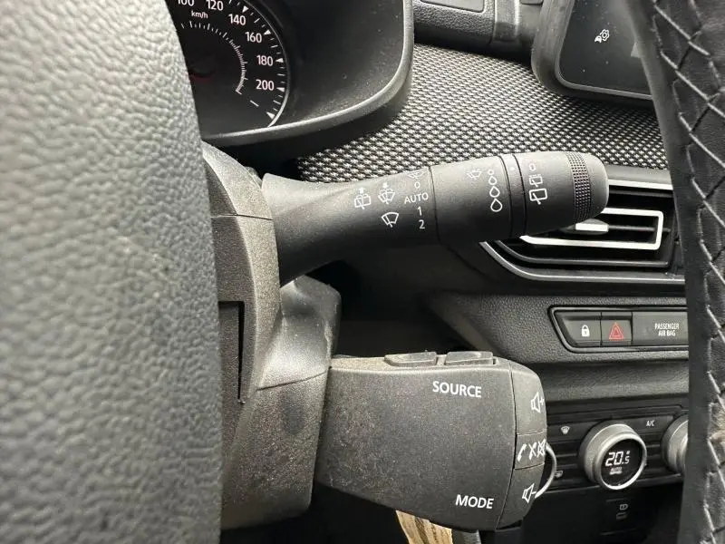 Gros plan sur les commandes au volant du Dacia Jogger 2025, avec tableau de bord et aérateur visibles en arrière-plan.