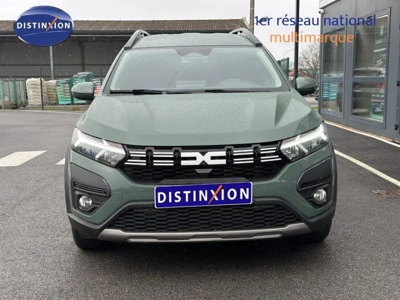 Vue frontale d'un Dacia Jogger 2025 en kaki lichen avec calandre noire et logo central distinctif, sur parking extérieur.