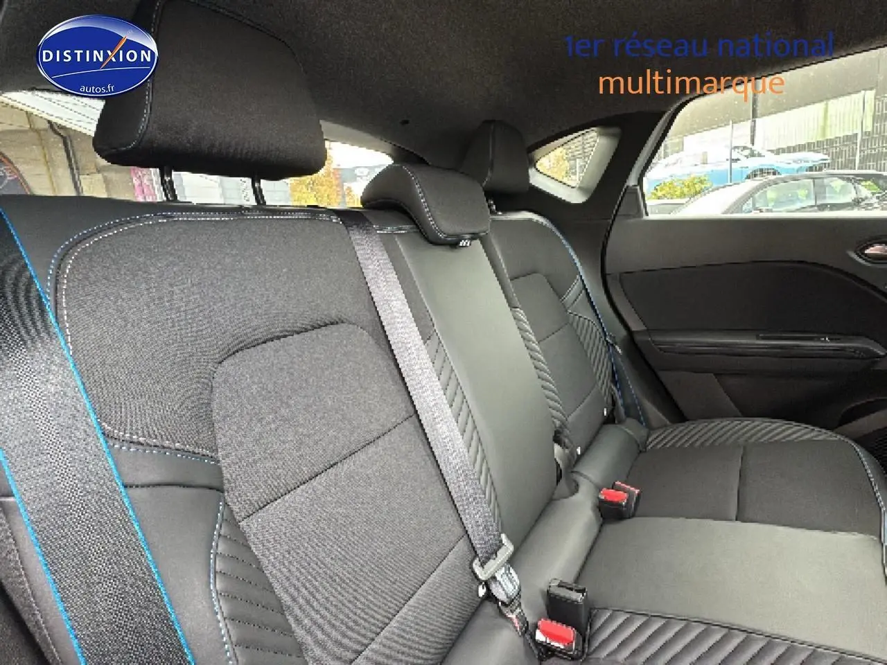 Vue intérieure montrant la banquette arrière noire avec surpiqûres bleues du Renault Captur 1.8 e-tech hybride 2025.