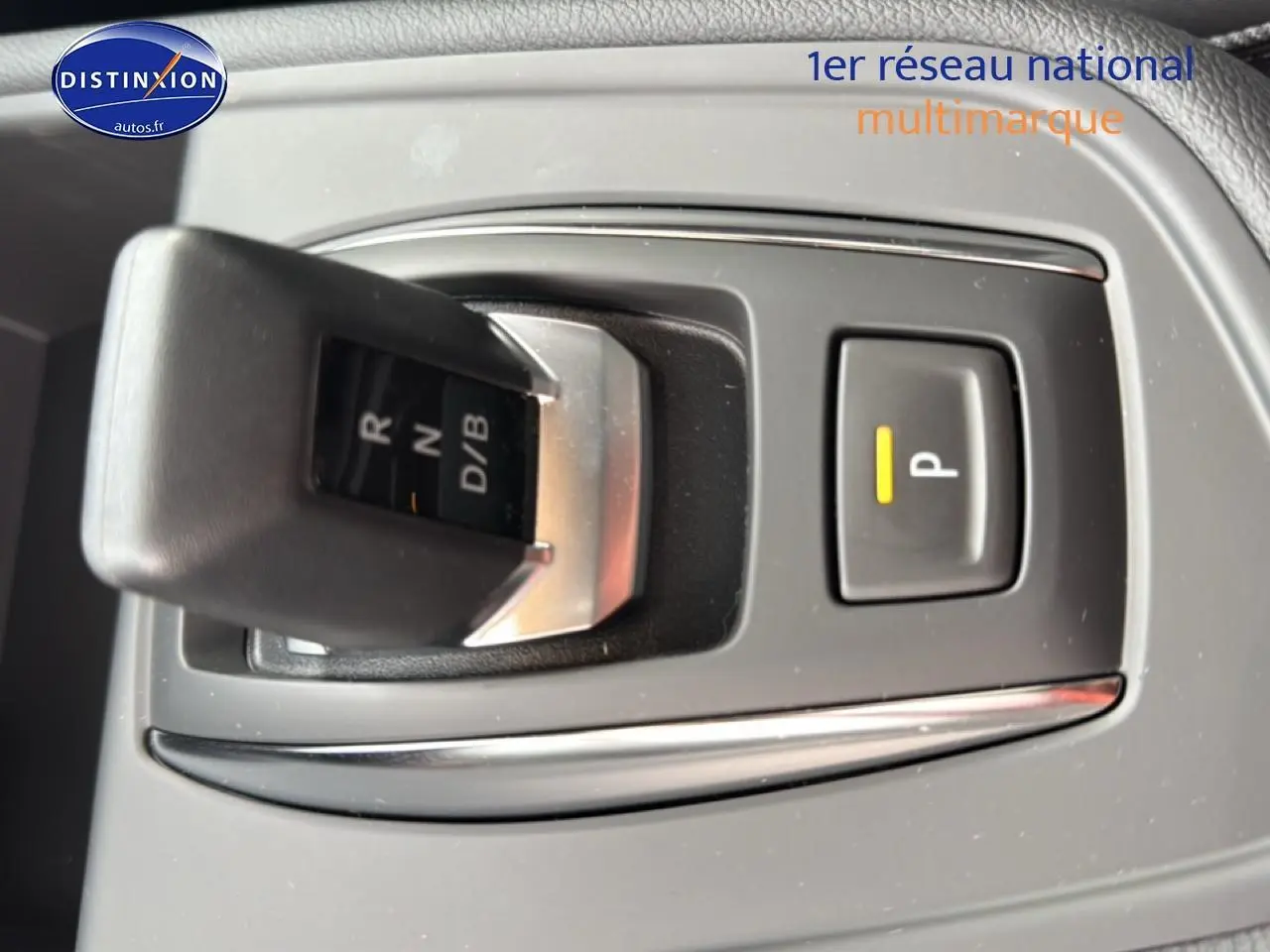 Le levier de boîte automatique et bouton de parking du Renault Captur 1.8 e-tech gris, vue rapprochée intérieure.