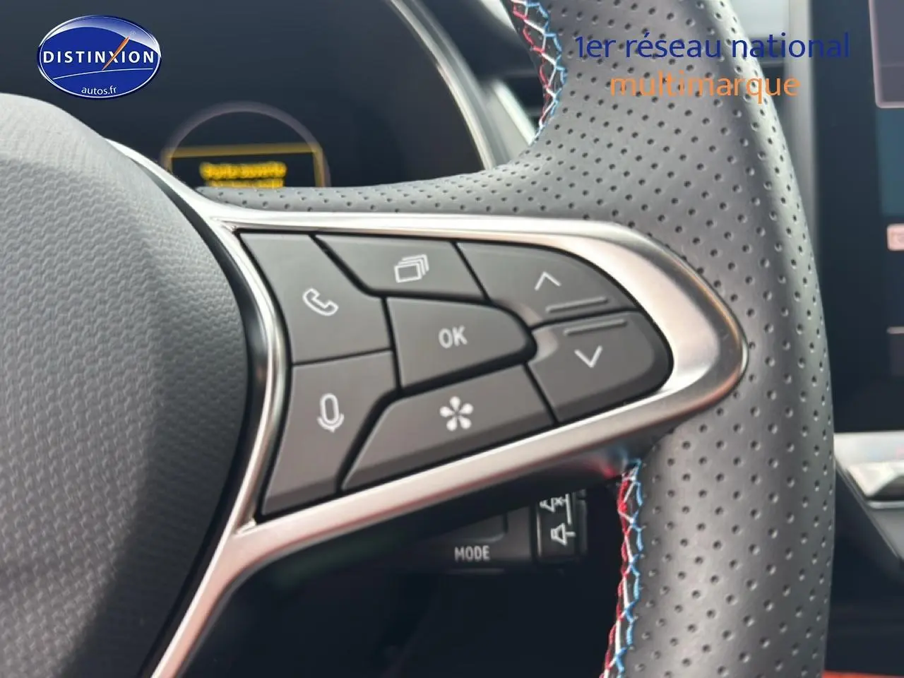 Gros plan sur le volant cuir perforé avec commandes multifonctions et surpiqûres tricolores du Renault Captur hybride 2025.