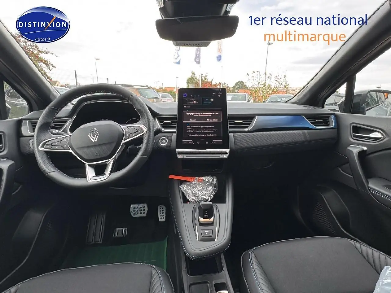 Vue intérieure avant du Renault Captur gris rafale, mettant en valeur le volant cuir multifonction et l'écran tactile vertical central.