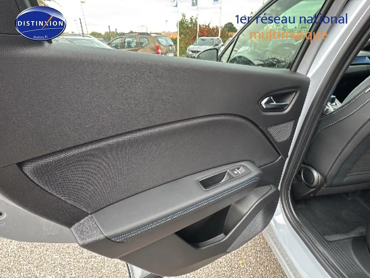 Vue intérieure de la porte arrière gauche du Renault Captur gris rafale, avec surpiqûres bleues et haut-parleur intégré.