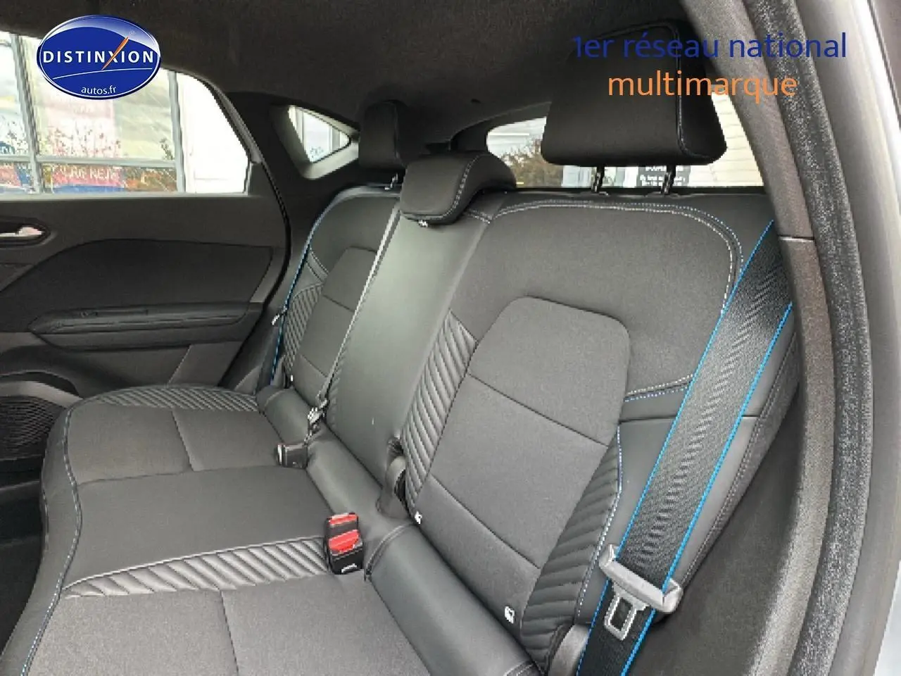 Vue intérieure de la banquette arrière du Renault Captur gris rafale, avec surpiqûres bleues et ceintures visibles.