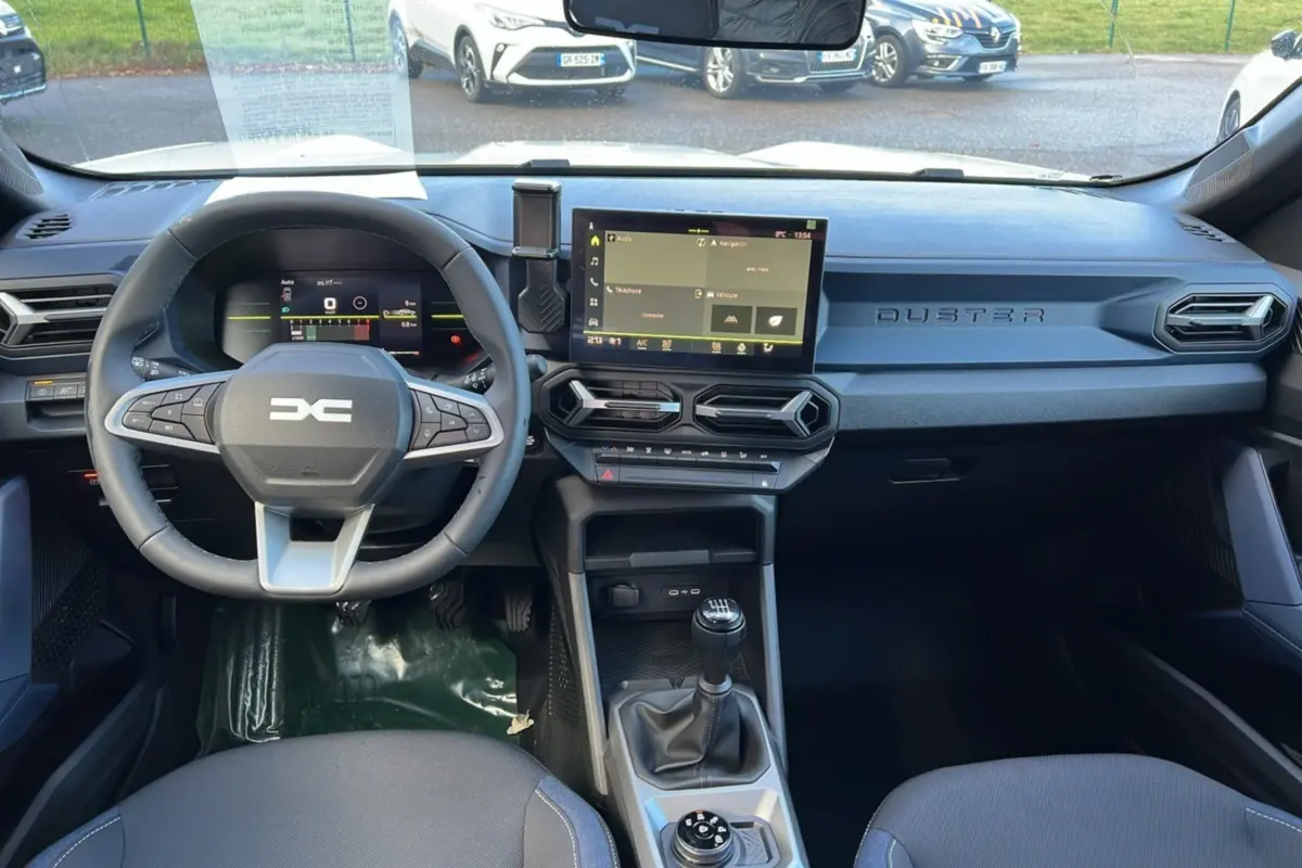 Vue intérieure avant du Dacia Duster 2026 noir nacré, montrant le volant cuir, la boîte manuelle et l'écran tactile central.