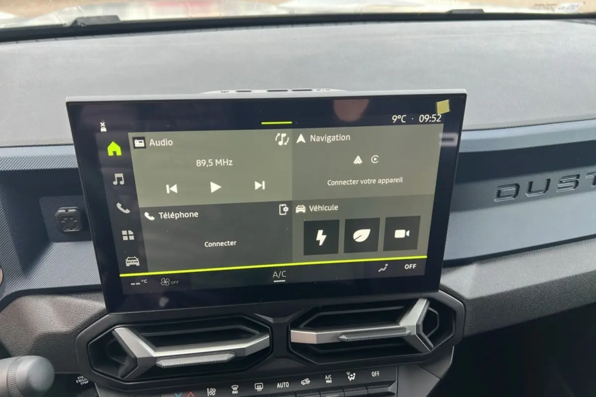 Vue rapprochée de l’écran tactile central et de la planche de bord gris foncé avec logo DUSTER embossé.
