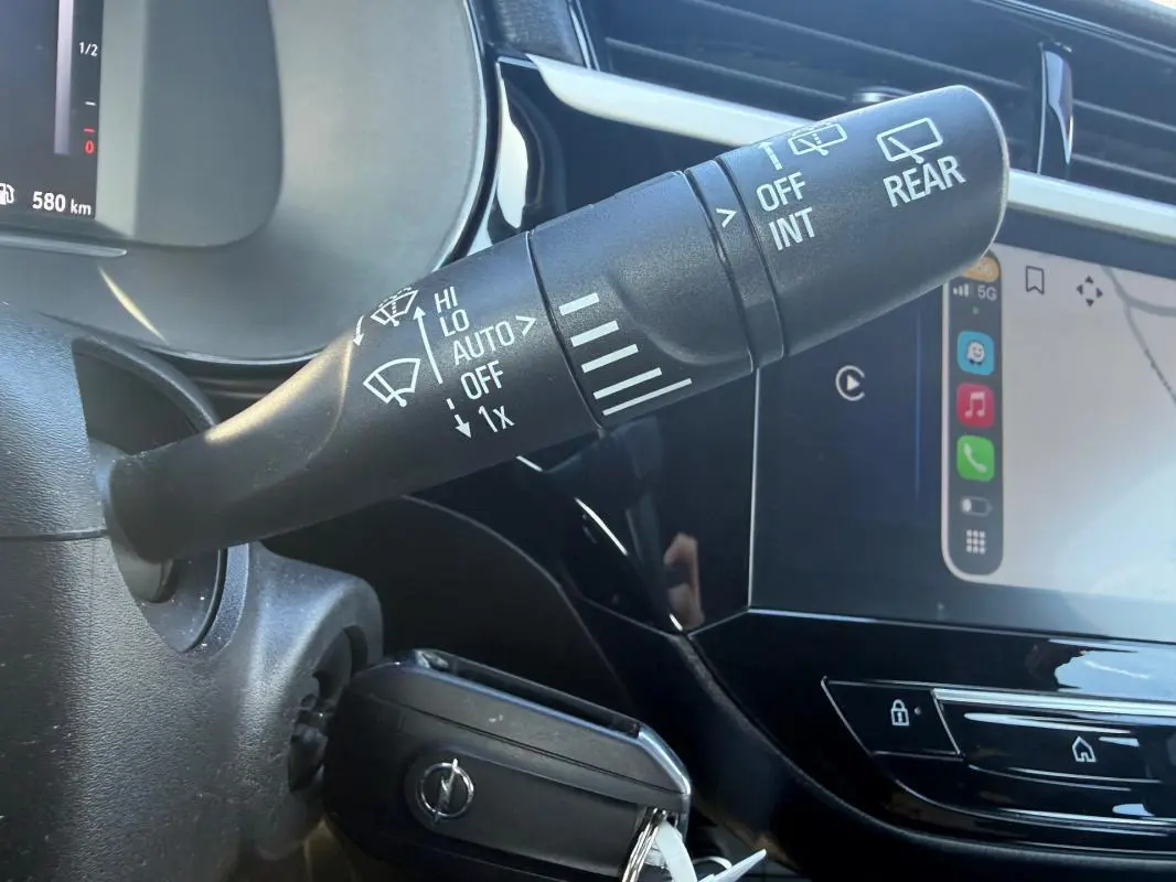 Gros plan sur la commande d’essuie-glace et l’écran tactile du tableau de bord d’une Opel Corsa rouge 2025.