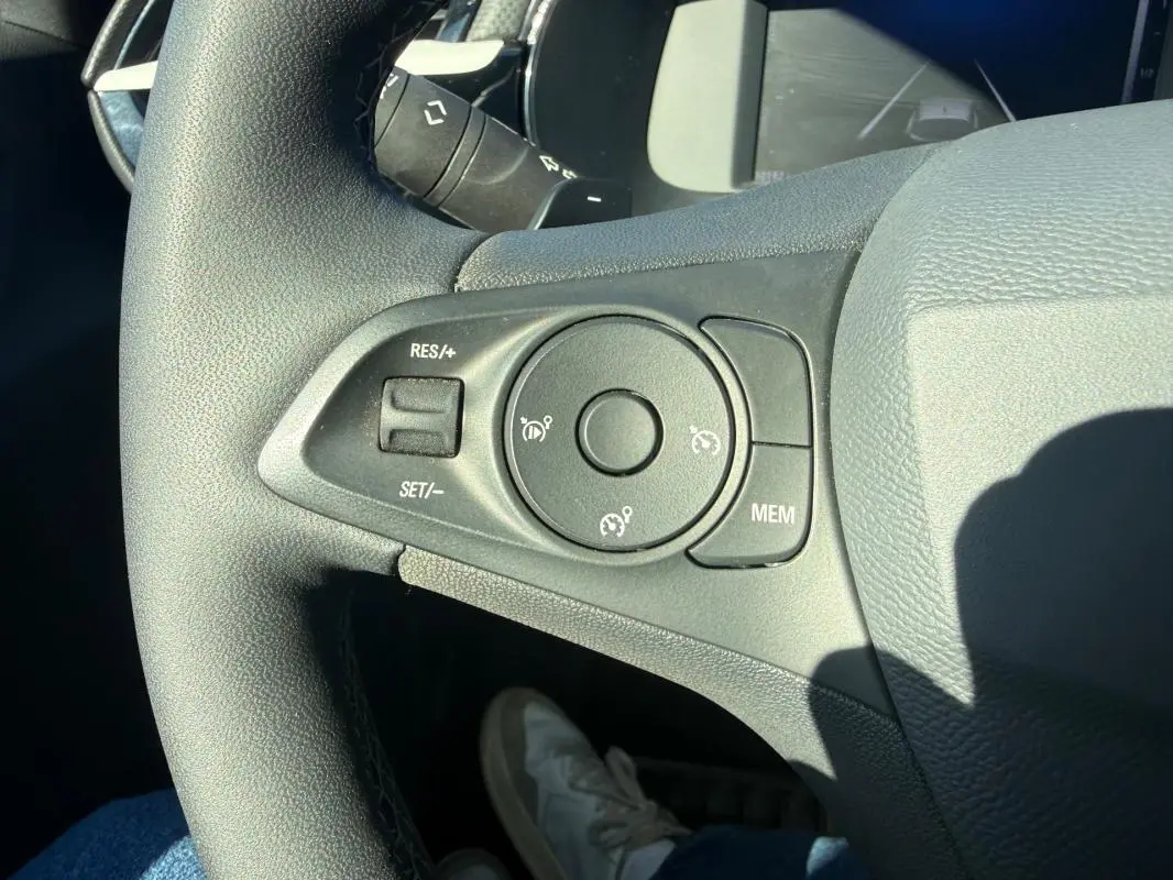 Gros plan sur les commandes de régulateur de vitesse au volant d'une Opel Corsa rouge 2025, version hybride essence.
