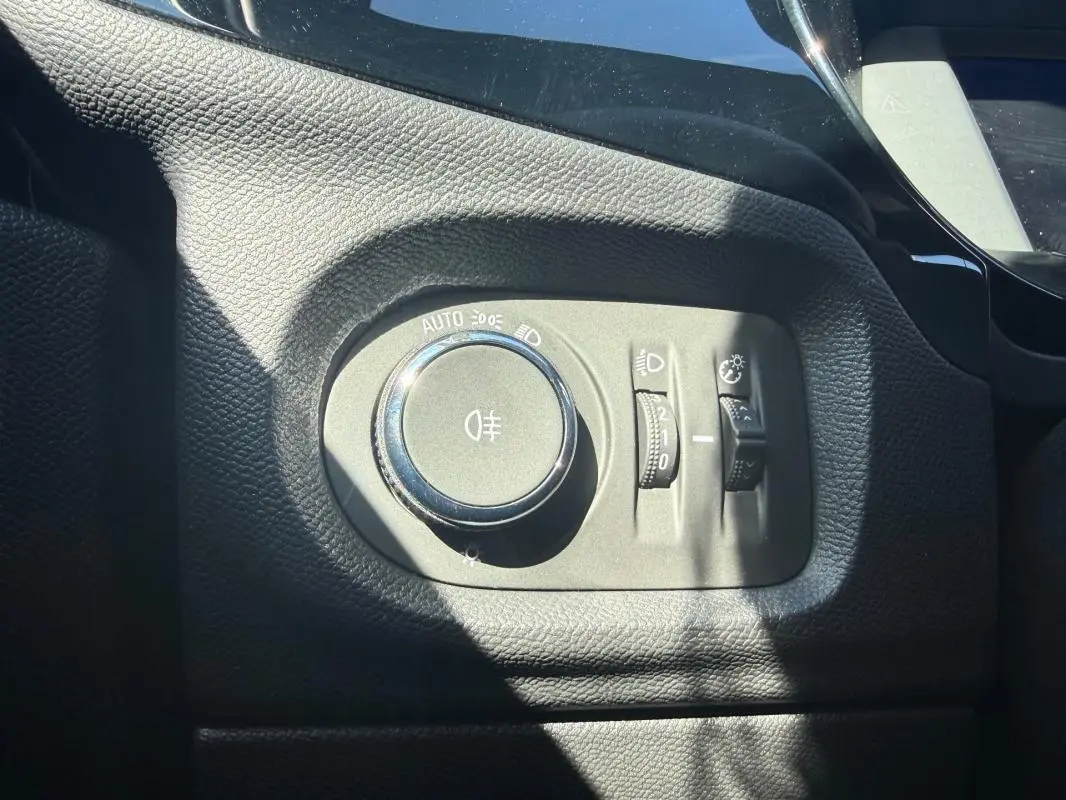 Gros plan sur la molette de réglage des phares dans l’habitacle noir de l’Opel Corsa rouge 2025.