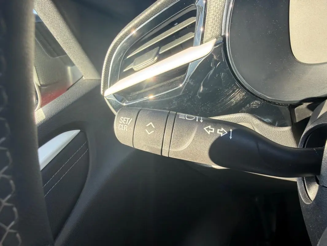 Détail du commodo de clignotant à gauche dans l’habitacle d’une Opel Corsa rouge 2025, version 1.2 Turbo Hybrid.