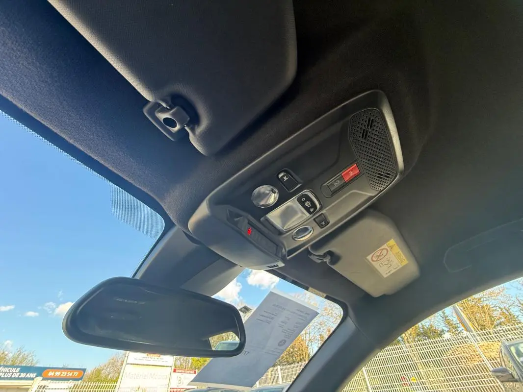 Vue intérieure du toit et du rétroviseur d'une Opel Corsa rouge 2025, avec commandes et plafonnier visibles.