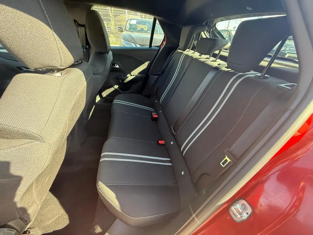 Vue intérieure arrière côté droit de l’Opel Corsa rouge 2025, montrant les sièges arrière avec bandes blanches.