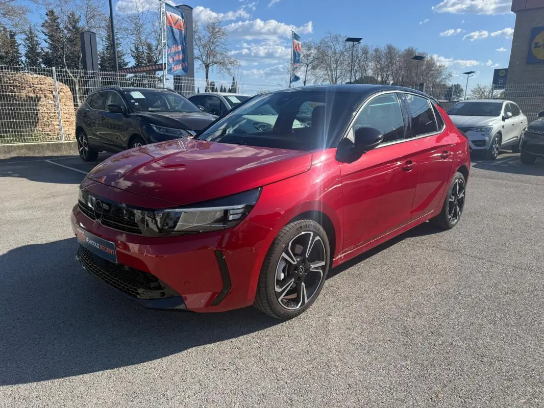 Opel Corsa 2025 rouge vue 3/4 avant droit, toit noir, jantes alliage noires et détails sportifs visibles.