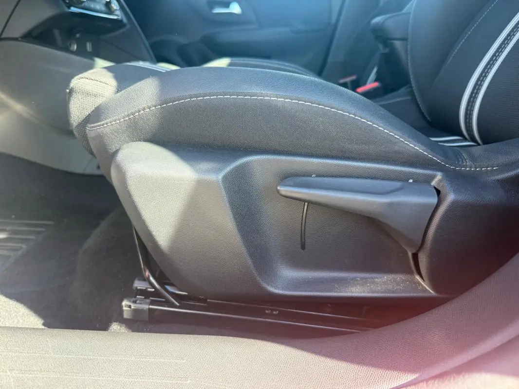 Détail du réglage manuel du siège avant côté conducteur d'une Opel Corsa rouge 2025, tissu noir.