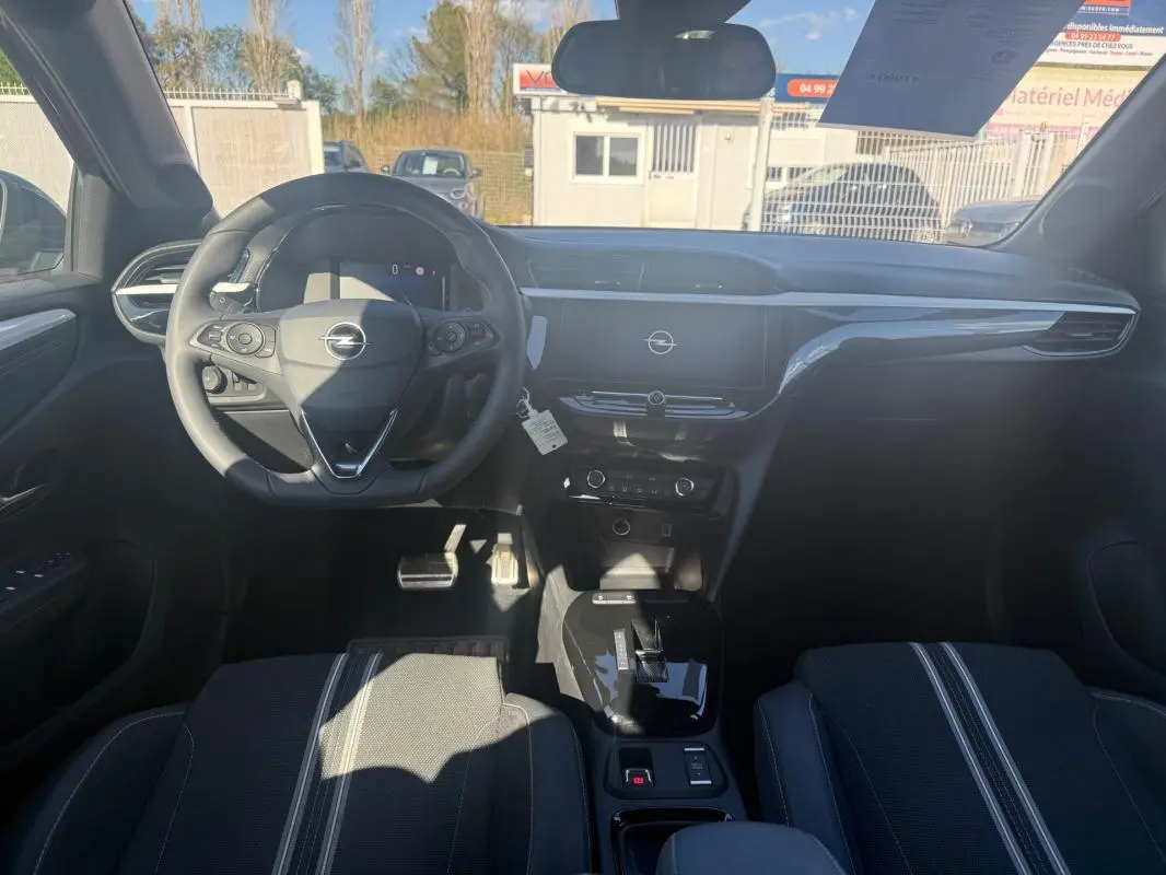 Vue intérieure avant de l’Opel Corsa 2025, tableau de bord noir avec écran central et volant multifonction.