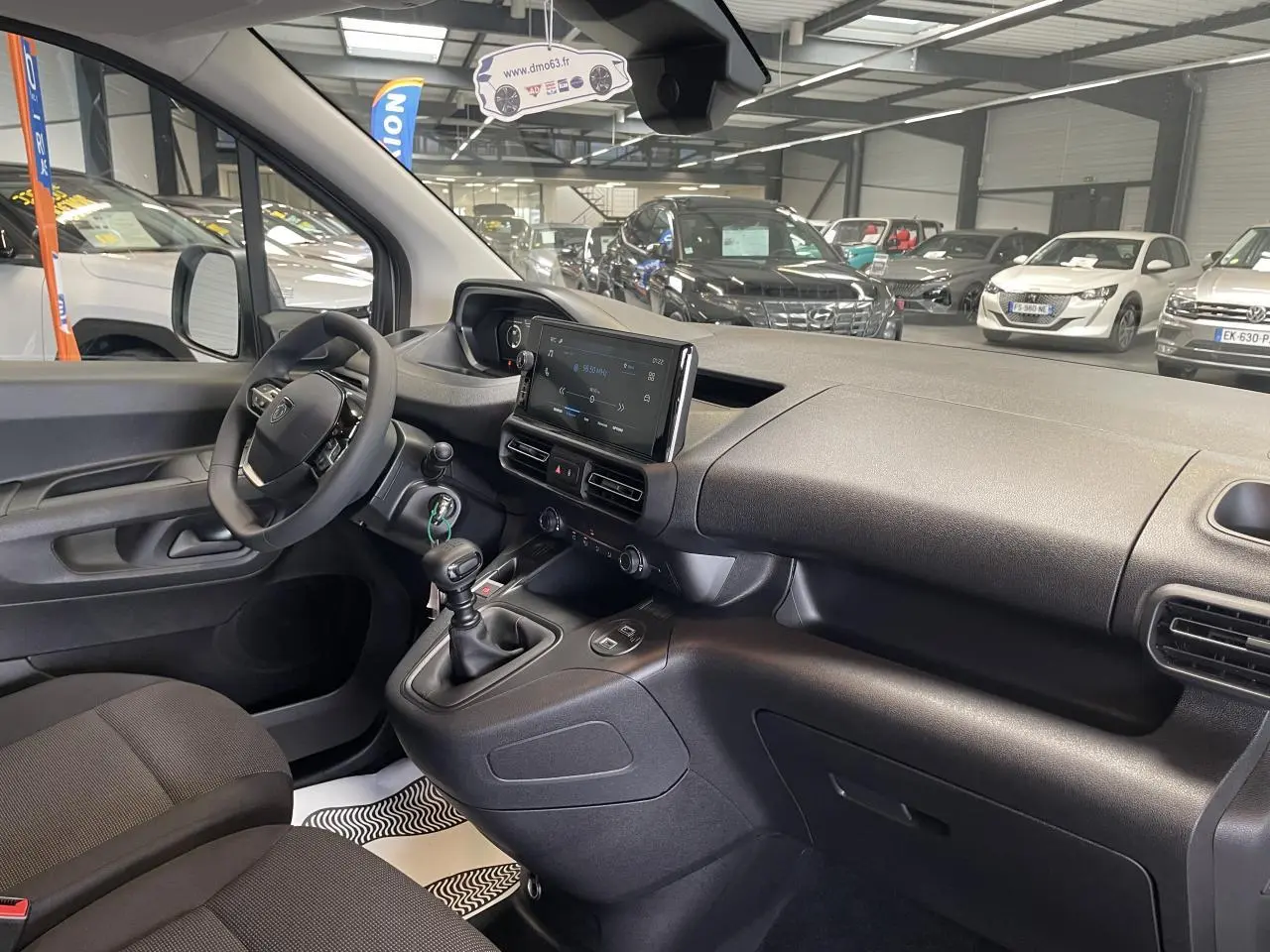 Vue intérieure côté conducteur du Peugeot Partner 2026, montrant tableau de bord noir avec écran tactile et boîte manuelle.