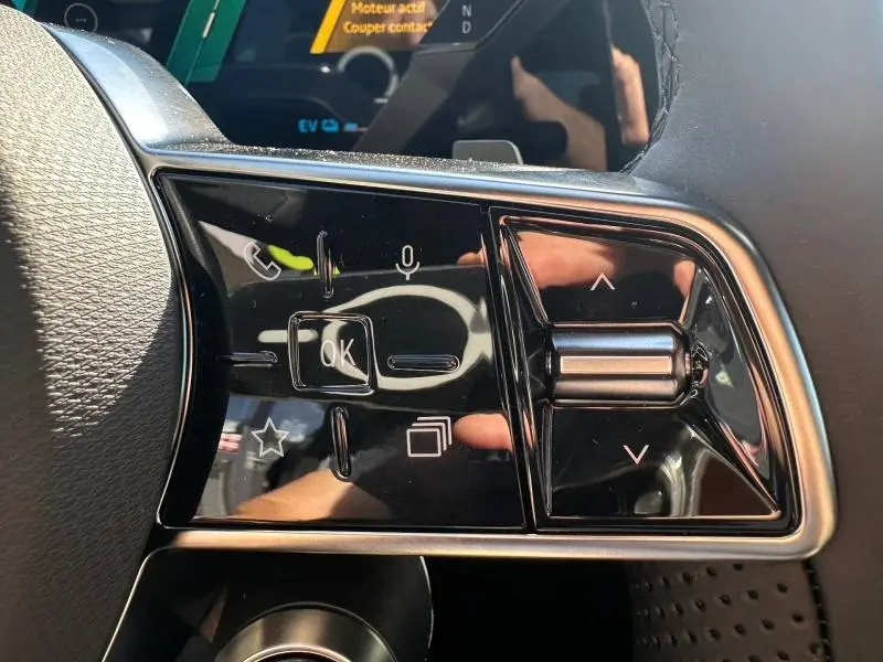 Gros plan sur les commandes noires brillantes au volant du Renault Austral gris Schiste, version hybride 2025.
