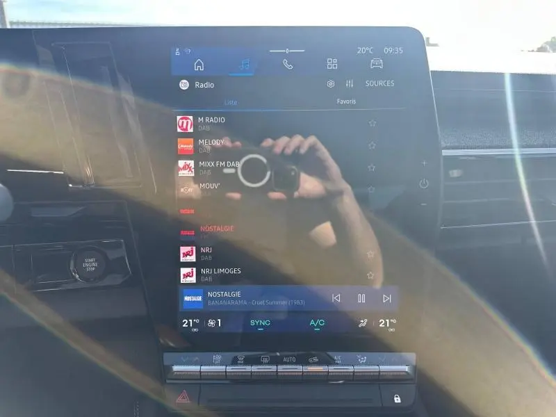 Écran tactile central du tableau de bord du Renault Austral 2025, affichant les radios DAB avec reflet de lumière.