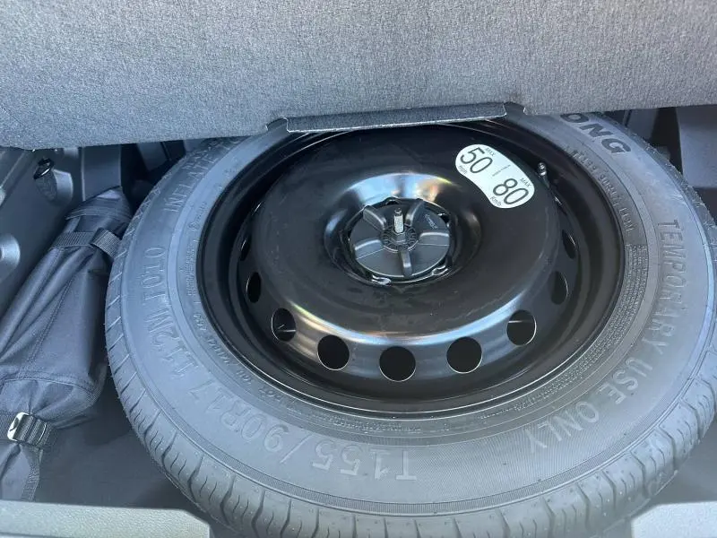 Roue de secours noire en acier dans le coffre du Renault Austral 2025, version hybride gris schiste toit noir.