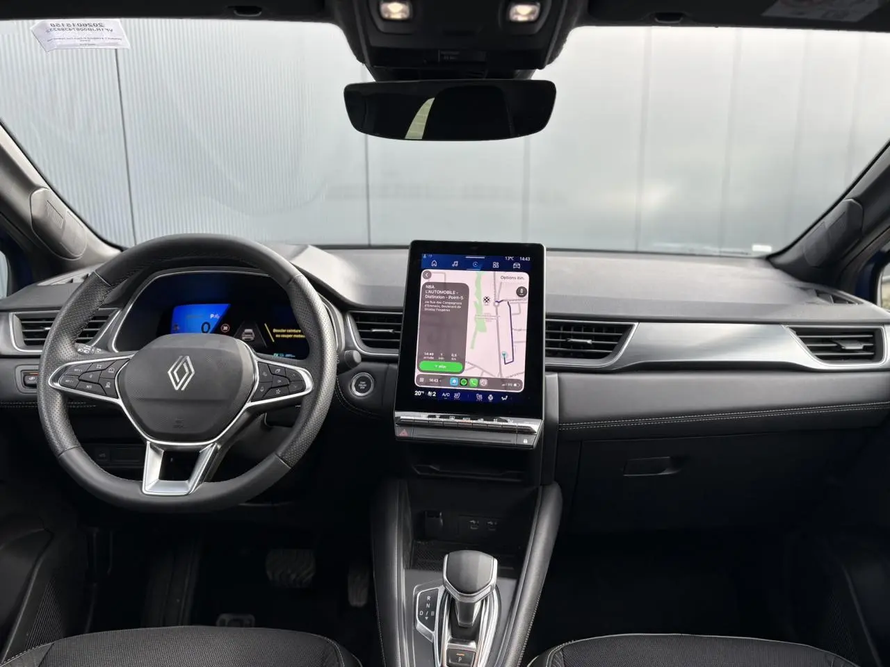 Vue frontale de l'intérieur du Renault Symbioz 2025, tableau de bord noir avec écran tactile vertical et volant multifonction.