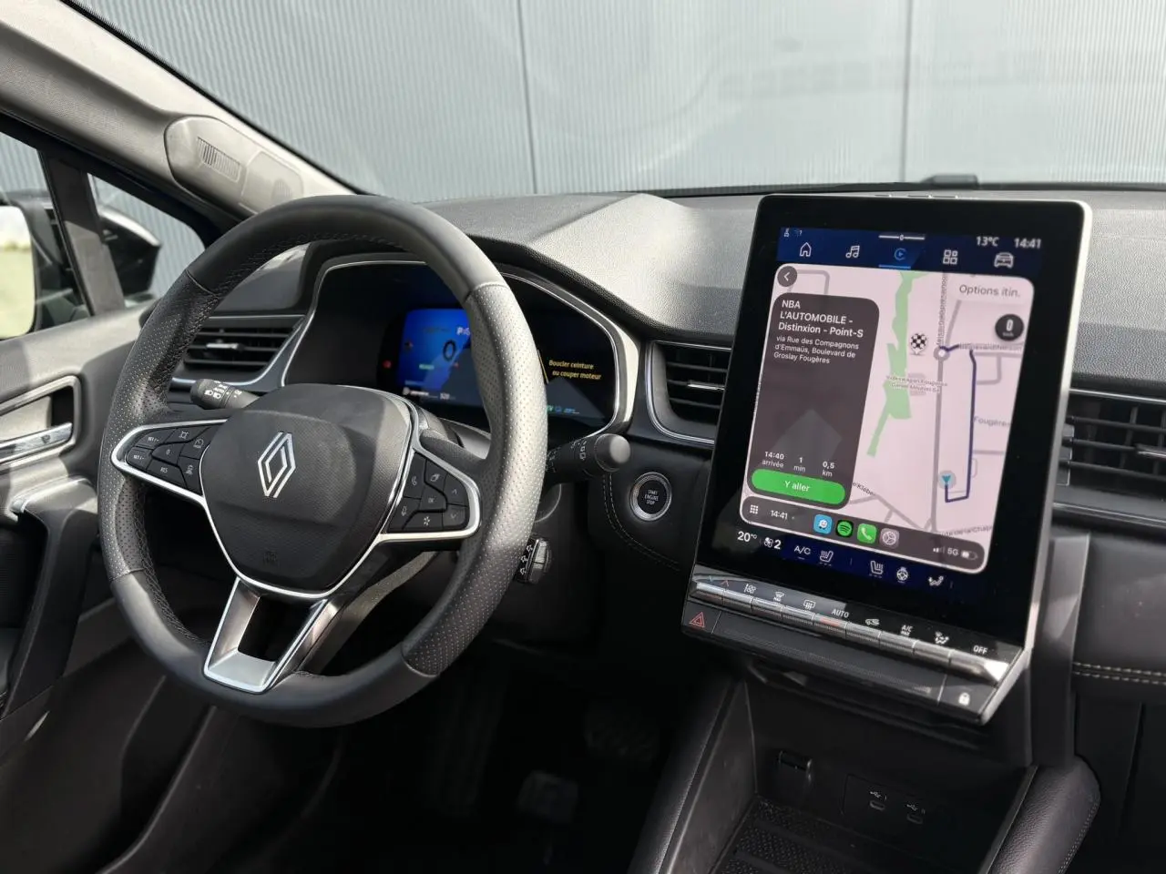 Vue intérieure du tableau de bord Renault SYMBIOZ 2025, volant multifonction et écran tactile vertical avec navigation affichée.