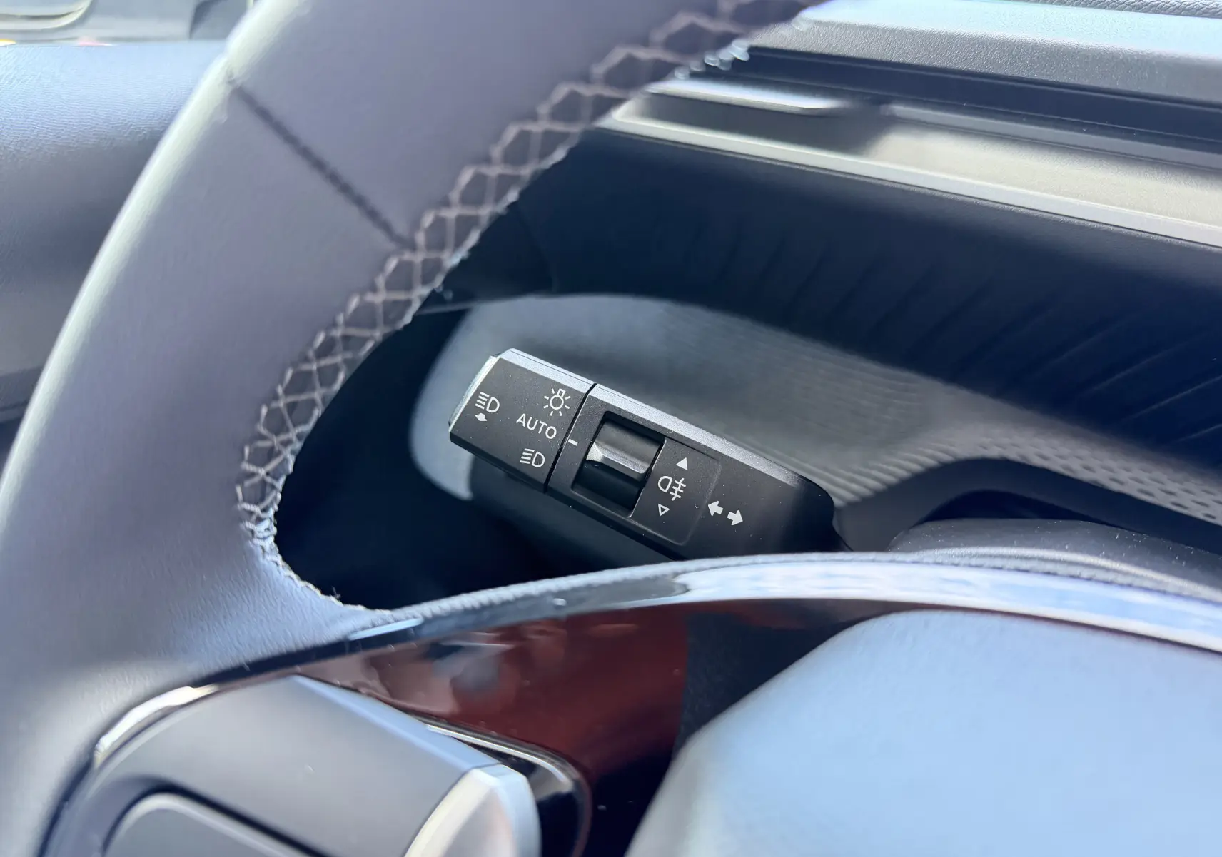 Gros plan sur la commande des feux et clignotants à gauche du volant dans l’habitacle gris du Citroën E-C3 2025.