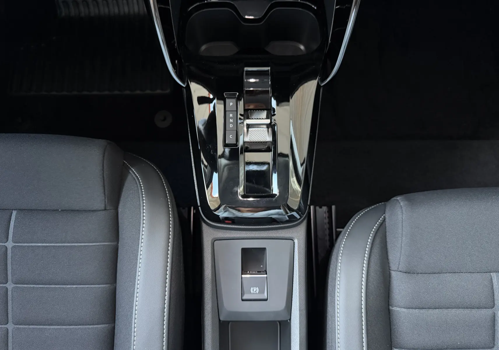 Vue plongeante sur la console centrale brillante et la sellerie tissu noir de la Citroën E-C3 113 MAX gris Mercury.